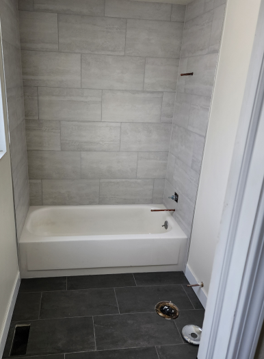 20230426_140655(1) 3 (2) a bathroom with a white bathtub and gray tile walls
