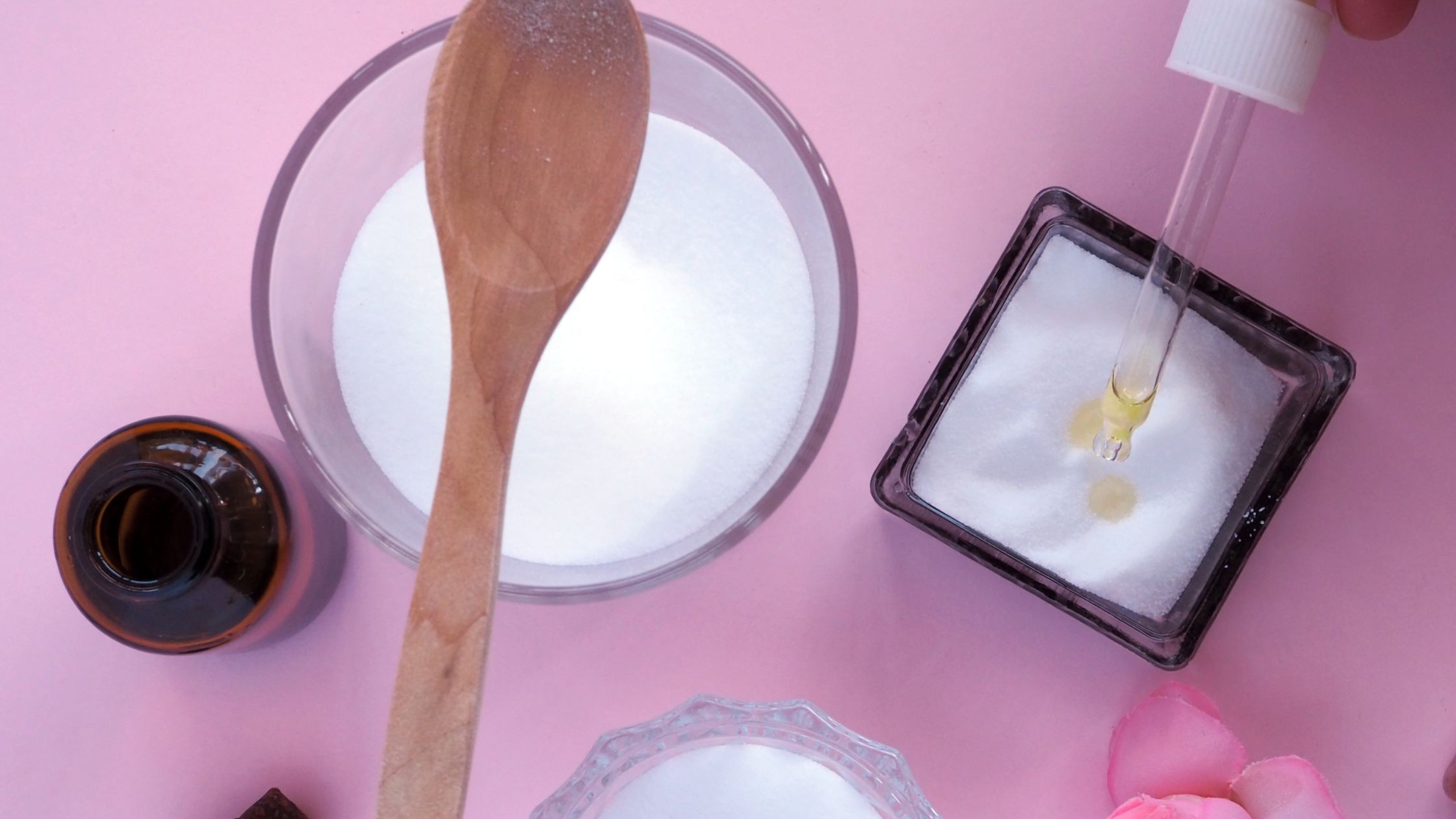 a spoon in a bowl of sugar and a container of salt