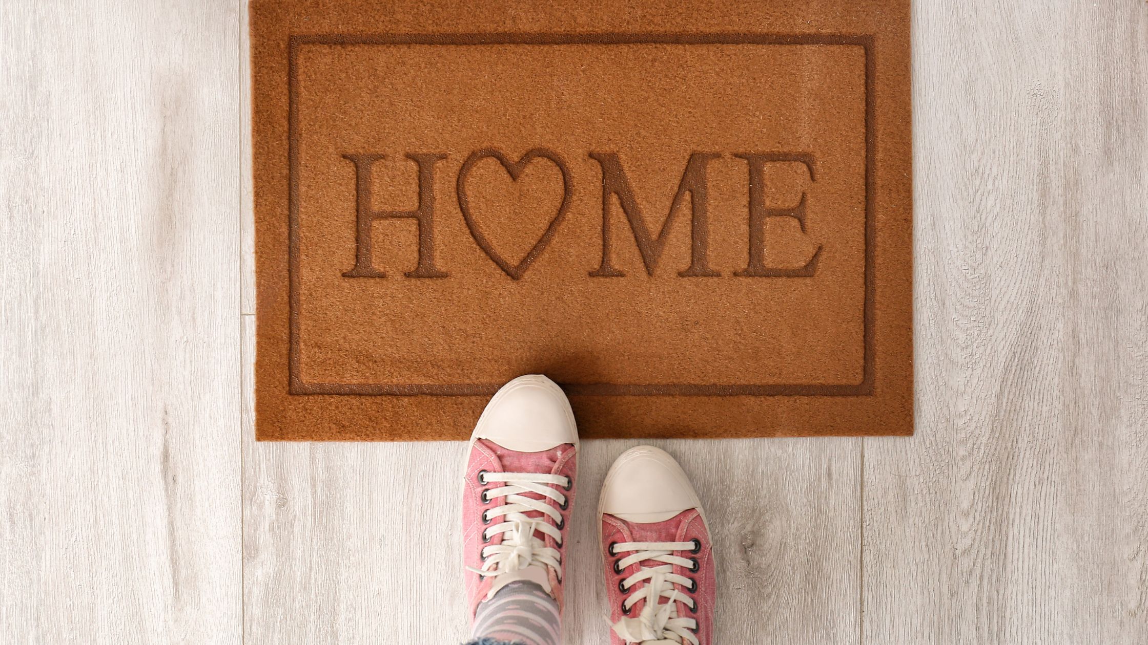 a person's feet standing in front of a brown doormat