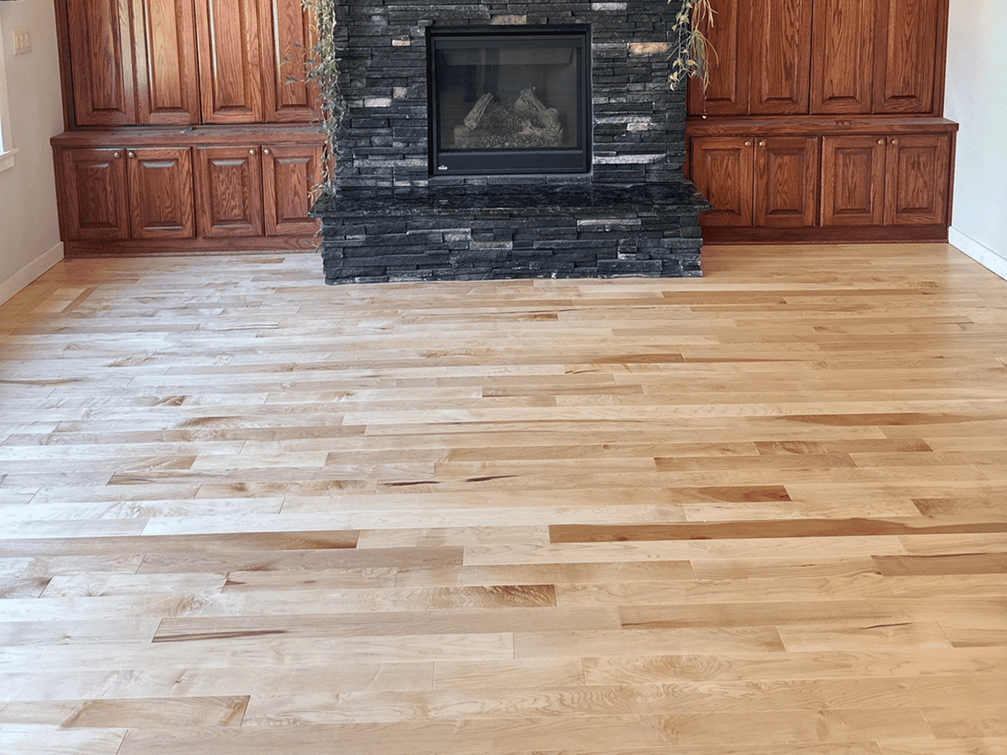 Beautiful hardwood flooring in a living room with a fireplace and built-in wooden cabinets.