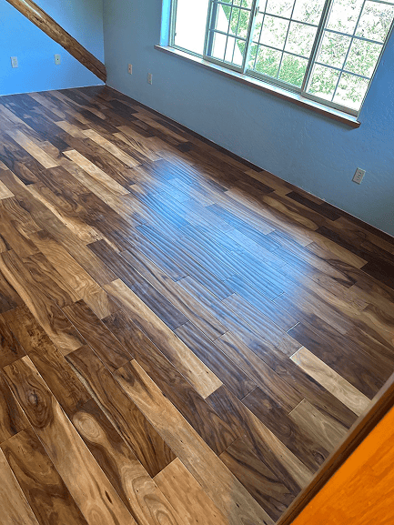Beautiful hardwood flooring installed in a bright room with large windows.