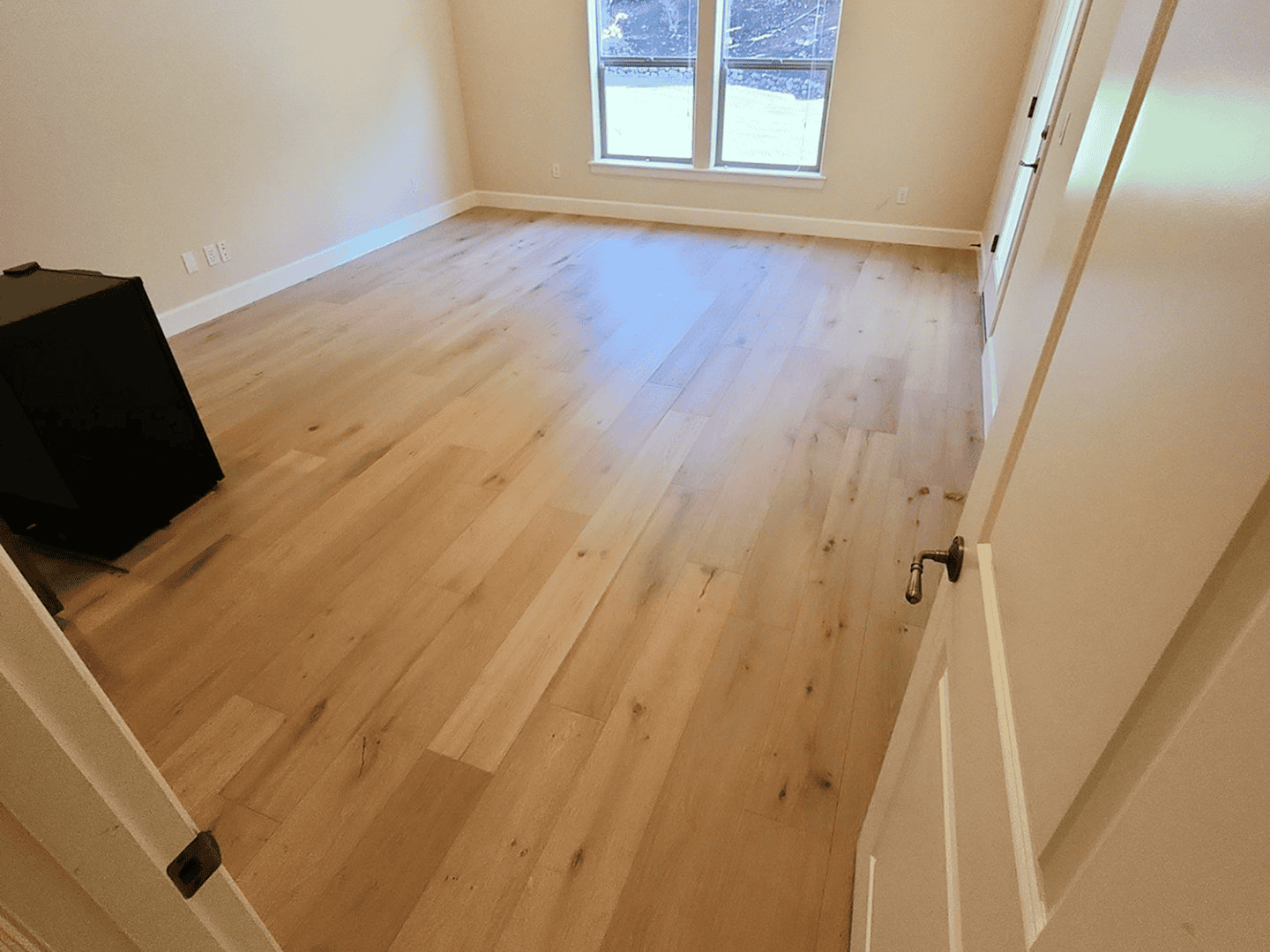 Beautiful hardwood flooring in a bright, empty room with large windows.