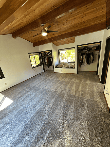 Spacious bedroom with new carpet, vaulted wooden ceiling, and large windows in Oregon.