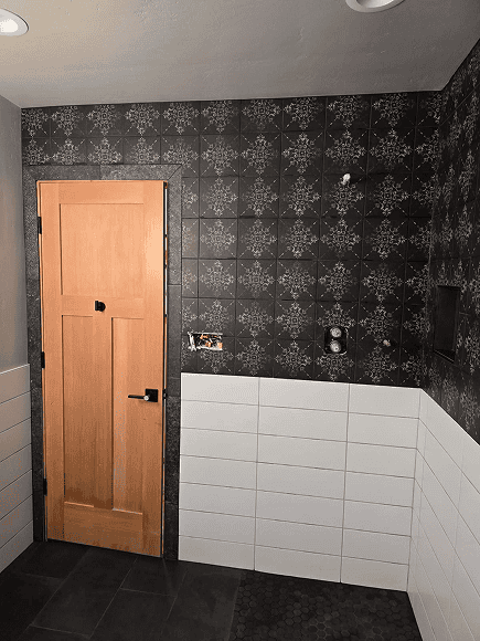 Bathroom tile installation with black patterned and white wall tiles.