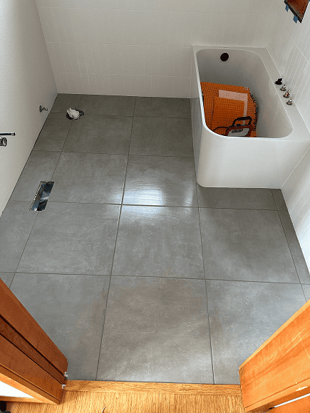 Bathroom tile installation with large gray tiles.