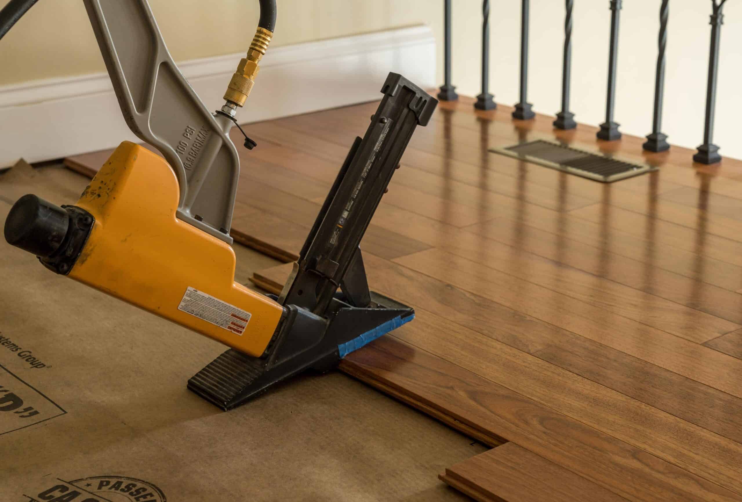Professional flooring installation with nail gun on hardwood floor in Oregon.